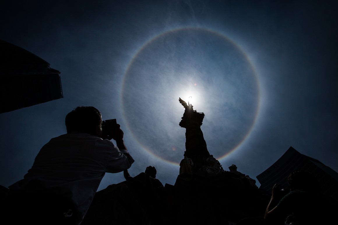 MEXICO CITY, MEXICO - MAY 21: A man takes a photo of the Solar Halo at the Angel de la Independencia, which took place in Mexico City on Thursday. A solar halo occurs when the light is refracted in ice crystals suspended in the atmosphere, on May 21, 2015 in Mexico City, Mexico. (Photo by Manuel Velasquez/LatinContent/Getty Images)