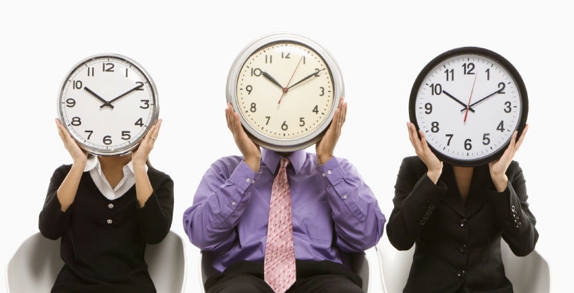 Multi-ethnic business people sitting holding clocks over faces.