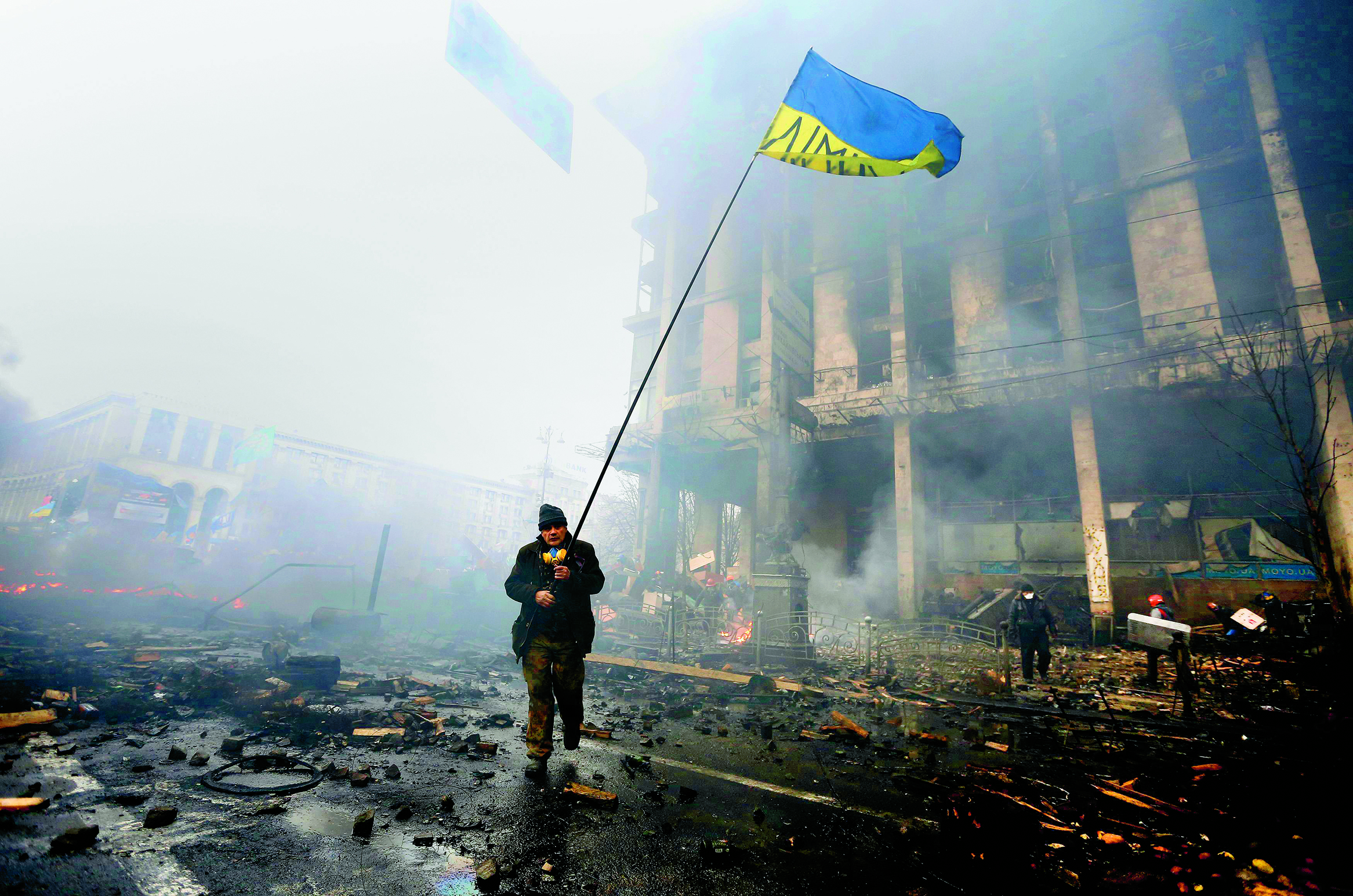 An anti-government protester holds a Ukranian flag as he advances through burning barricades in Kiev’s Independence Square February 20, 2014. Ukrainian protesters hurling petrol bombs and paving stones drove riot police from the central square in Kiev on Thursday despite a “truce” which embattled Ukrainian President Viktor Yanukovich said he had agreed with opposition leaders.  REUTERS/Yannis Behrakis (UKRAINE – Tags: CIVIL UNREST POLITICS TPX IMAGES OF THE DAY) ORG XMIT: YAN10