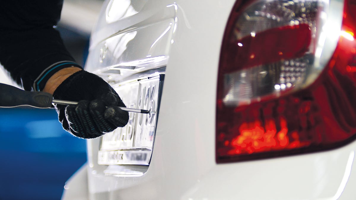 Mechanic in automobile service doing manual operations with car license plate number, telephoto