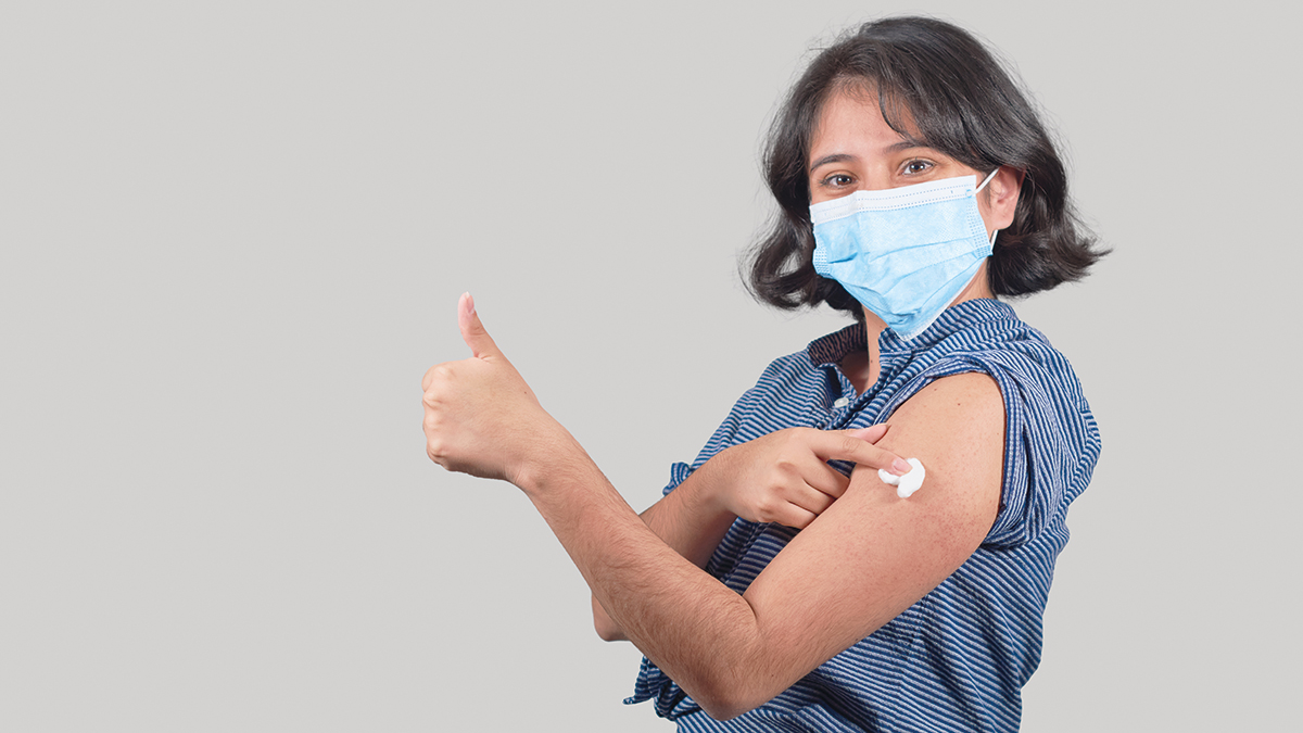 Young latin woman wearing freshly vaccinated face mask, isolated.