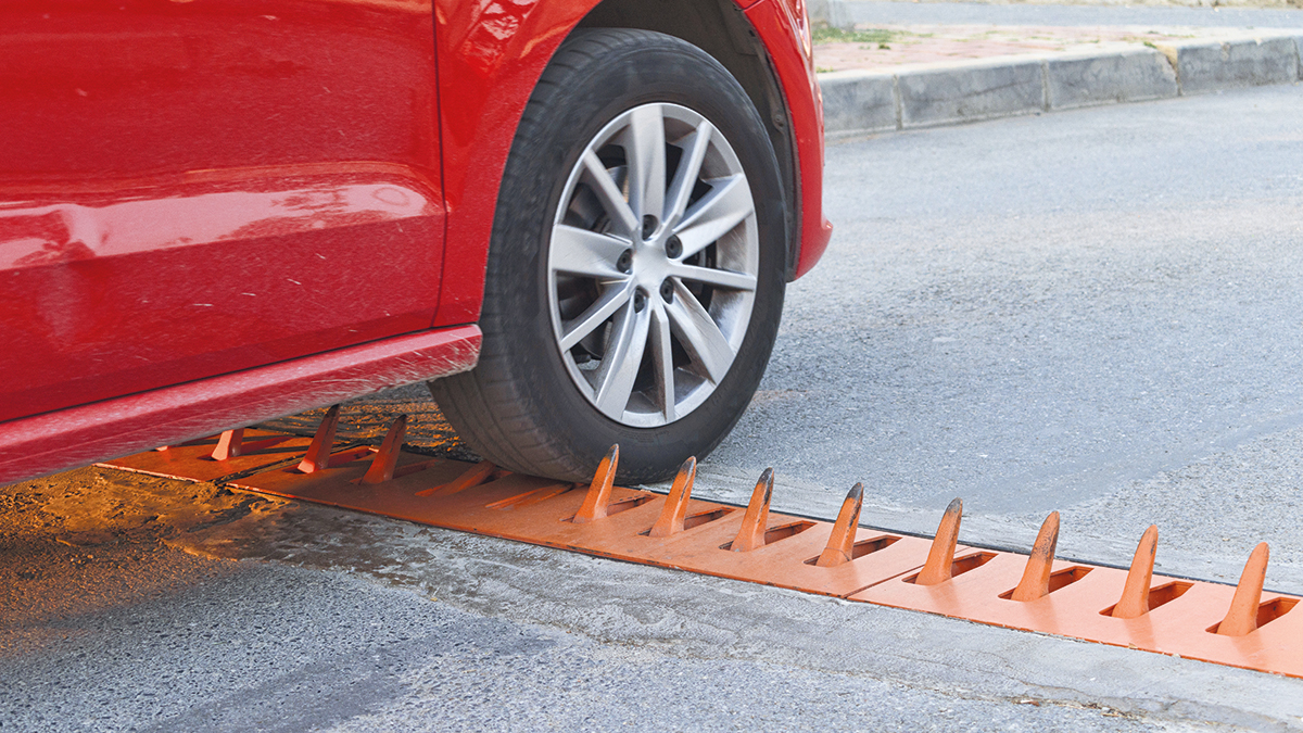 Road Spike Barrier. Car departing from the parking lot. wheel detail