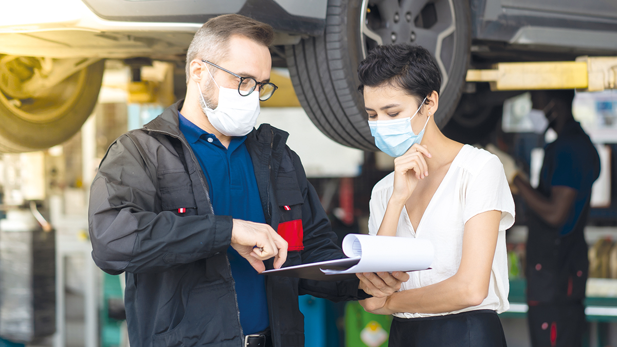 Mechanic man and woman customer wearing medical face mask protection coronavirus and check the car condition before delivery.