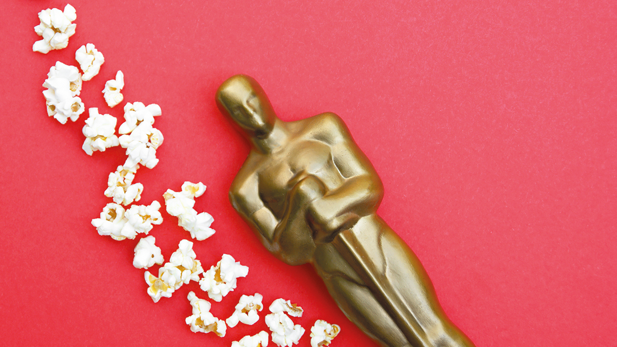 KHARKIV,UKRAINE – JULY 1, 2020: Plastic Oscar award on a red background with popcorn.
